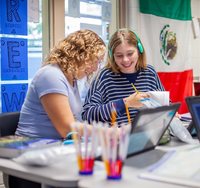 A teacher helping a student with something using a pencil and paper