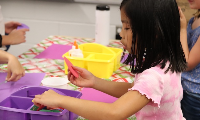 young student doing arts and crafts with glue and paper