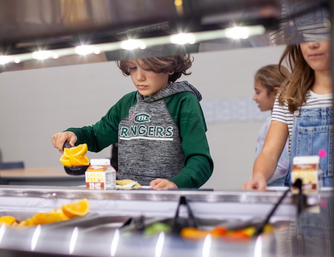 Boy scooping oranges onto plate